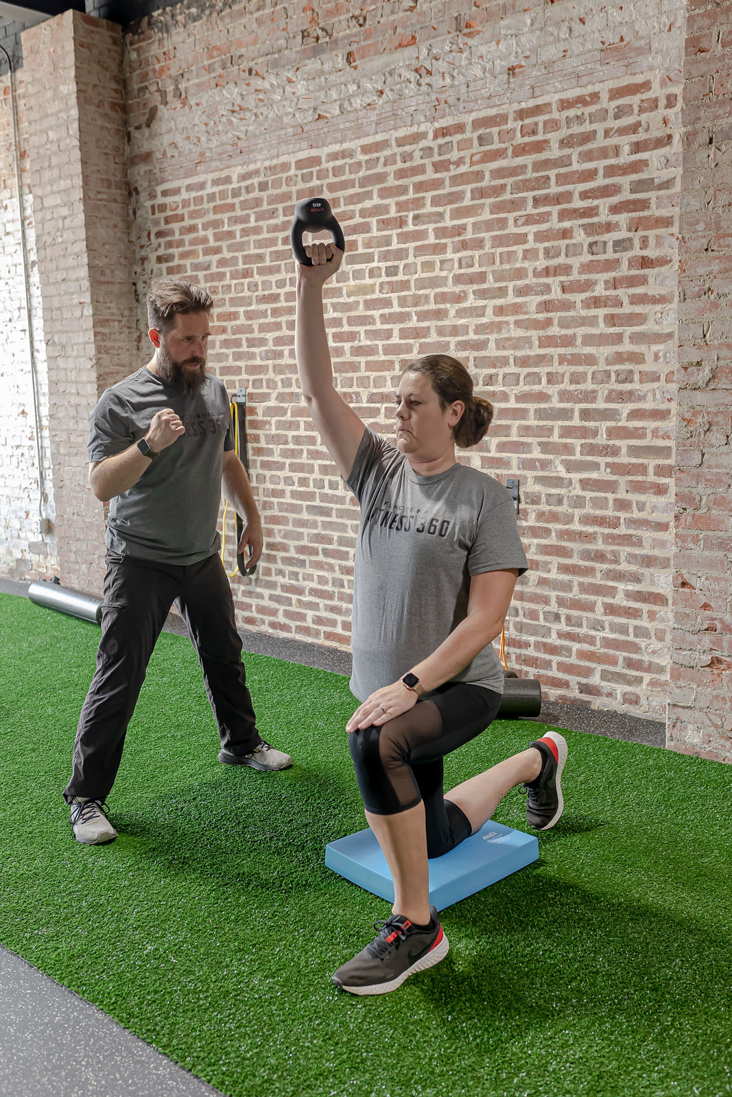Coach guiding a member through a kettlebell lunge