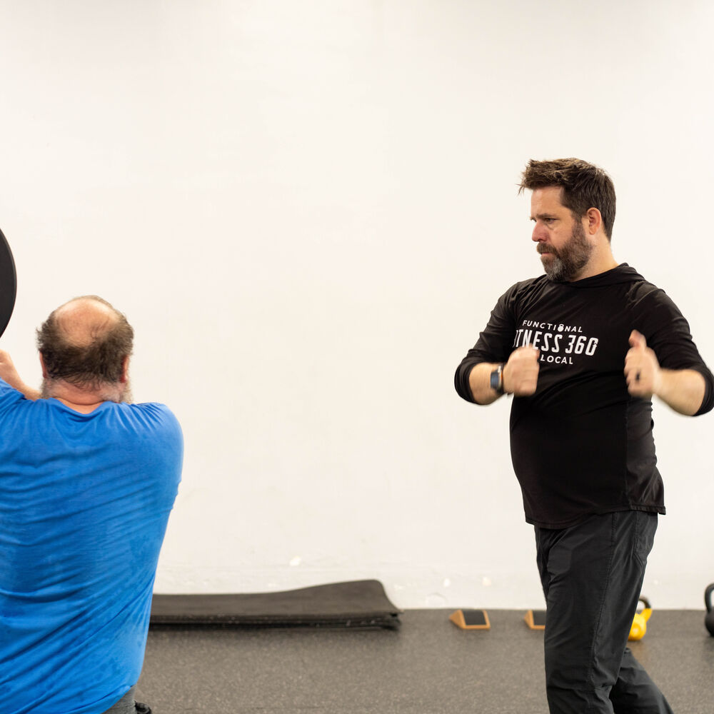 Coach demonstrating a plate exercise with a member