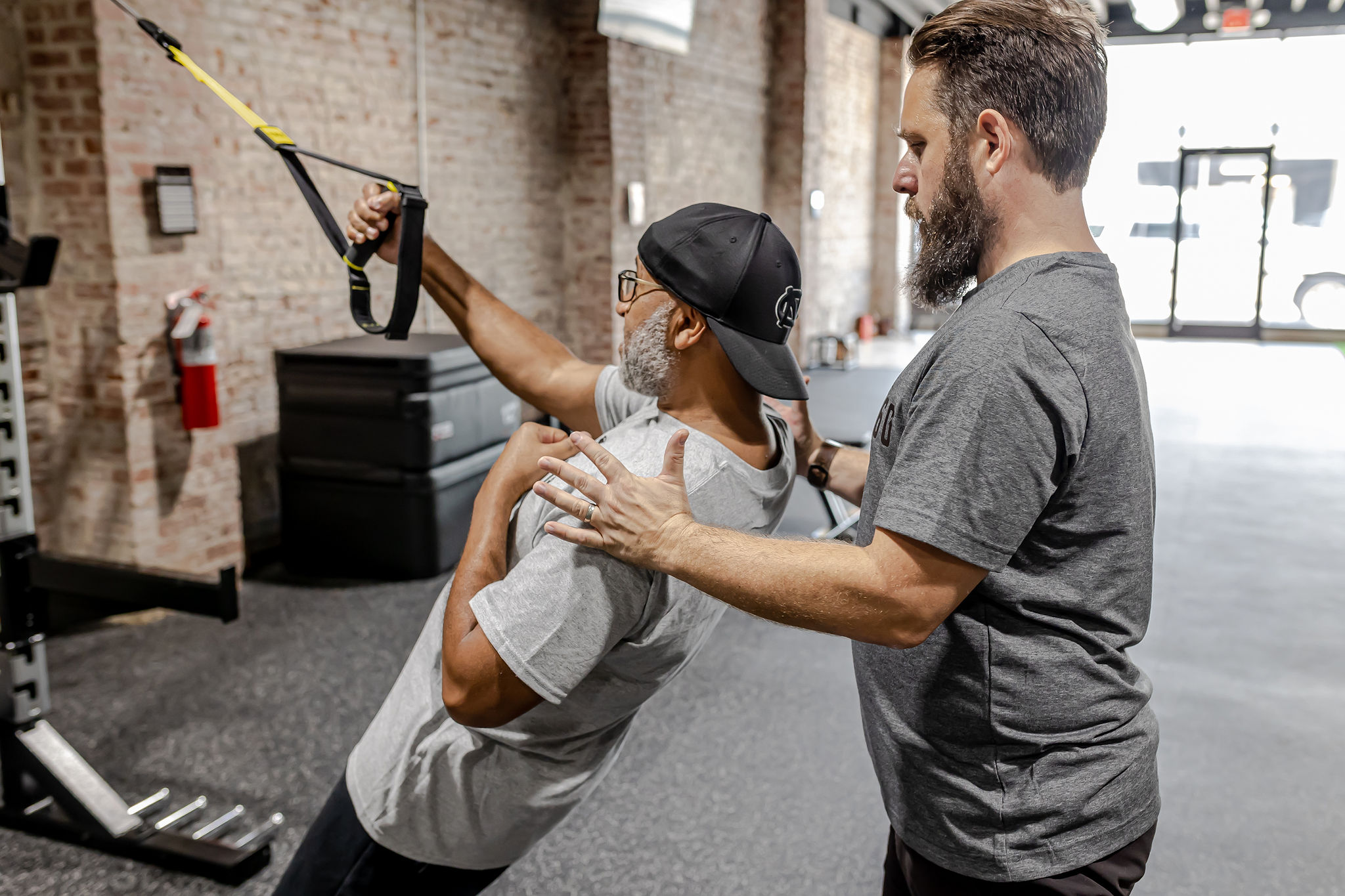 Coach assisting a member with TRX training