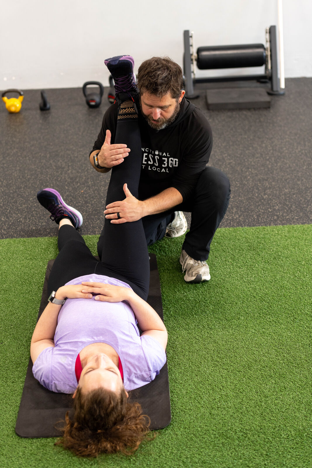 Coach guiding a member through mobility and recovery work