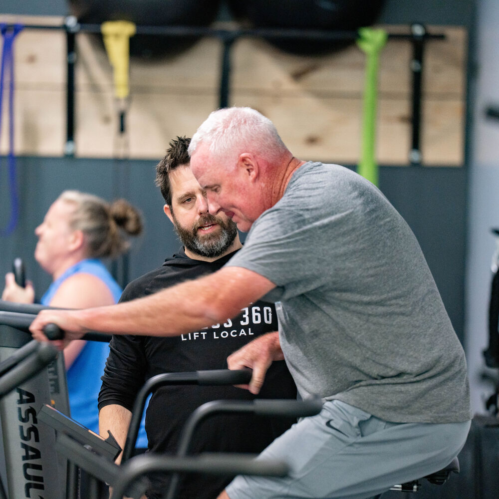 Members training together on assault bikes with their coach at FF360