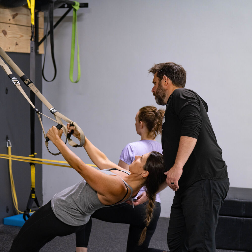 Member performing coached TRX rows