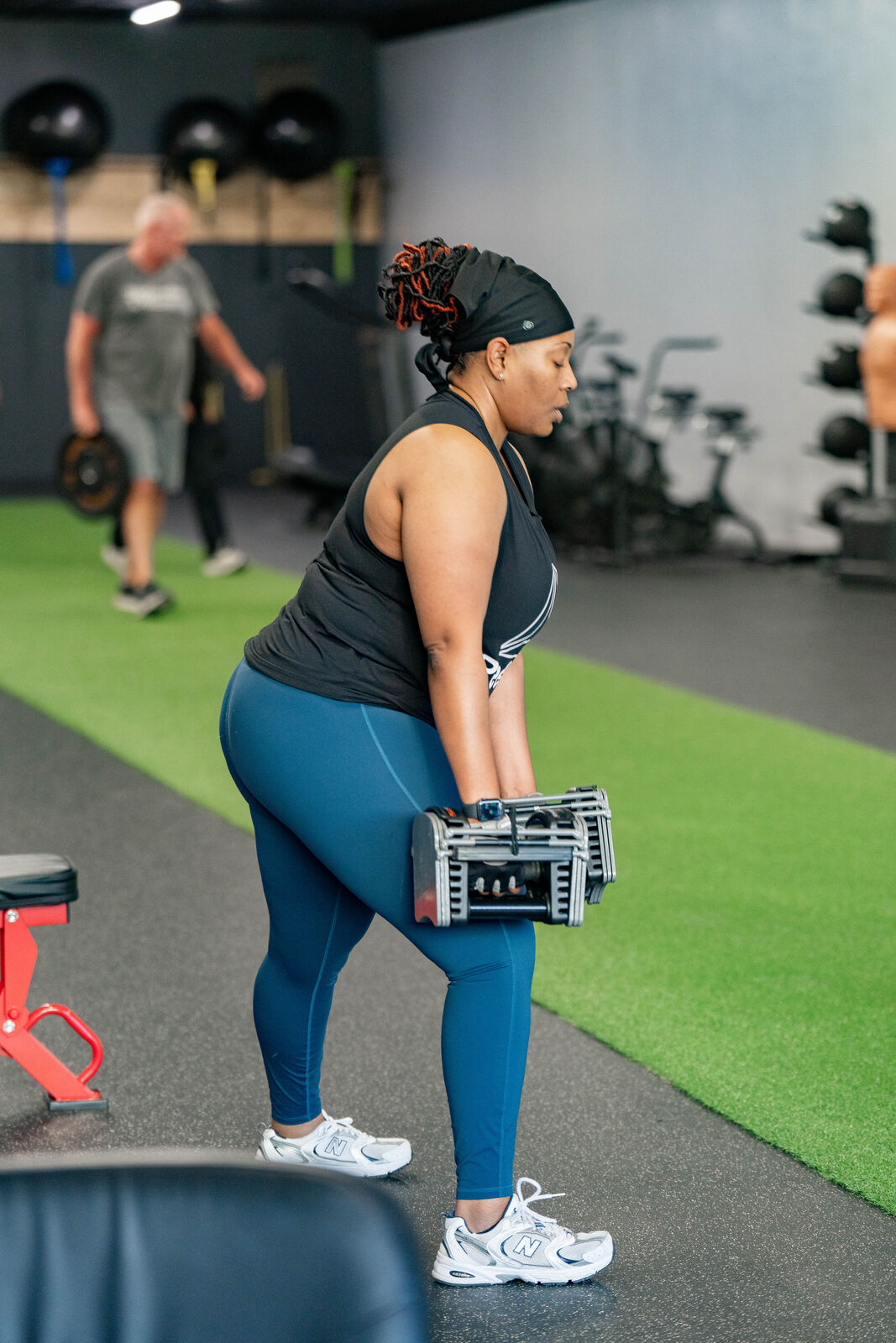 Member performing a coached dumbbell hinge on the turf